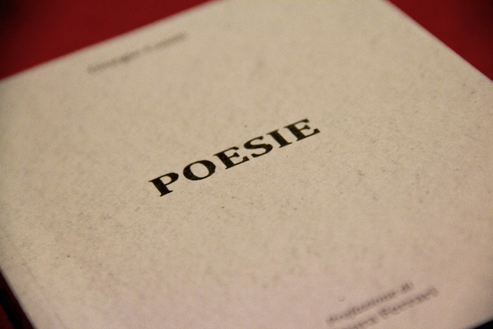 A detail on the book cover, the title “poesie” (poems) in the centre, written with a vintage font and some light stains in order to embellish it. The cover of rough paper consists of only a few elements, a way to emphasize this single central element and to enhance its meaning.  