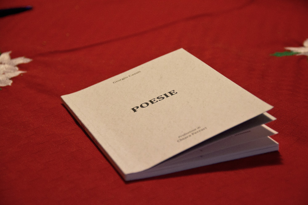 Il libro, completamente bianco, spicca su una tavola ricoperta da una tovaglia di un rosso caldo.